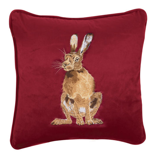 Cuscino in velluto rosso Wrendale Designs con ricamo di una lepre seduta, fotografato su sfondo bianco.