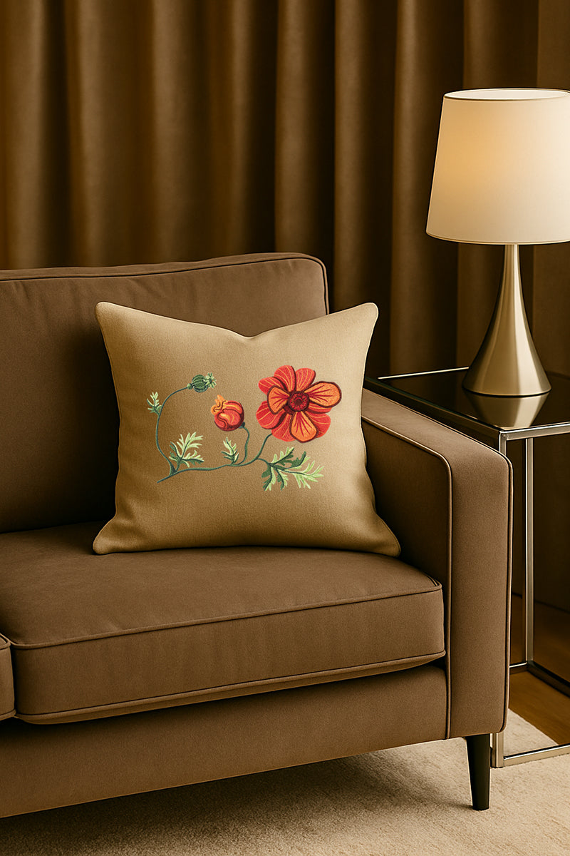 Cuscino decorativo in misto lino beige con ricamo 3D di anemone rosso, posato su un divano marrone in un soggiorno elegante con lampada dorata e tende scure.