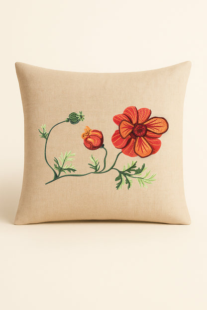 Cuscino quadrato in misto lino beige fotografato su sfondo neutro, con ricamo tridimensionale di anemone rosso, bocciolo arancione e foglie verdi in stile artigianale.