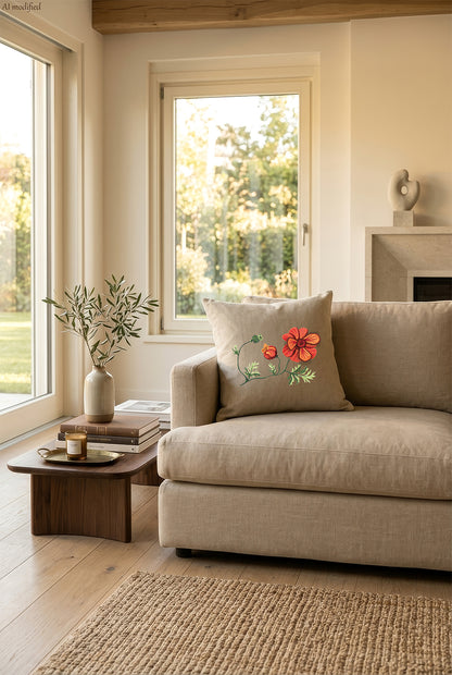 Cuscino in lino beige con ricamo a rilievo di anemone rosso e bocciolo arancione, personalizzabile appoggiato su un divano chiaro in un ambiente caldo e naturale, molto luminoso