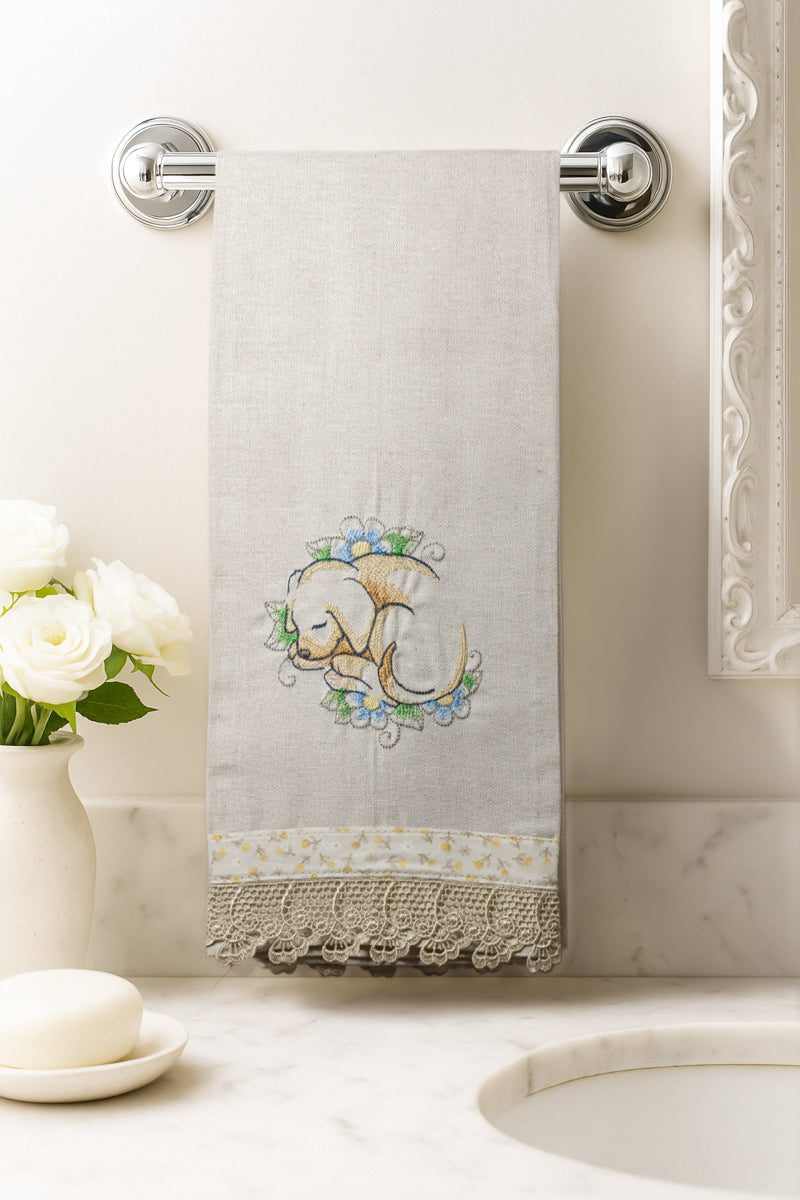 Asciugamano in cotone con ricamo cagnolino addormentato tra fiori azzurri, fotografato appeso in un bagno elegante.