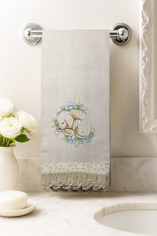Asciugamano in cotone con ricamo cagnolino addormentato tra fiori azzurri, fotografato appeso in un bagno elegante.