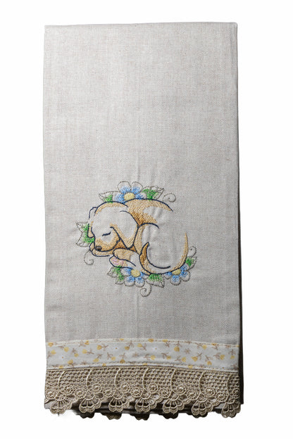 Asciugamano in cotone ricamato con cagnolino addormentato tra fiori azzurri su sfondo bianco.