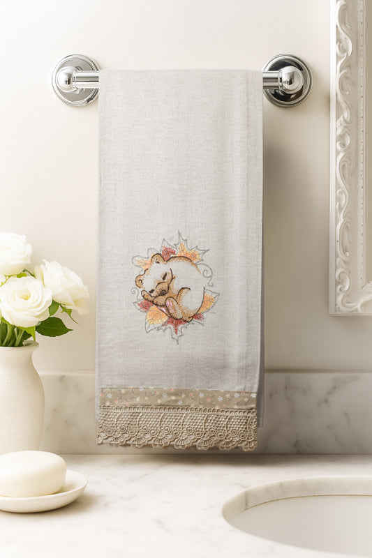 Asciugamano in cotone con ricamo orsetto coccolone addormentato tra foglie e fiori autunnali, fotografato appeso in un bagno elegante.
