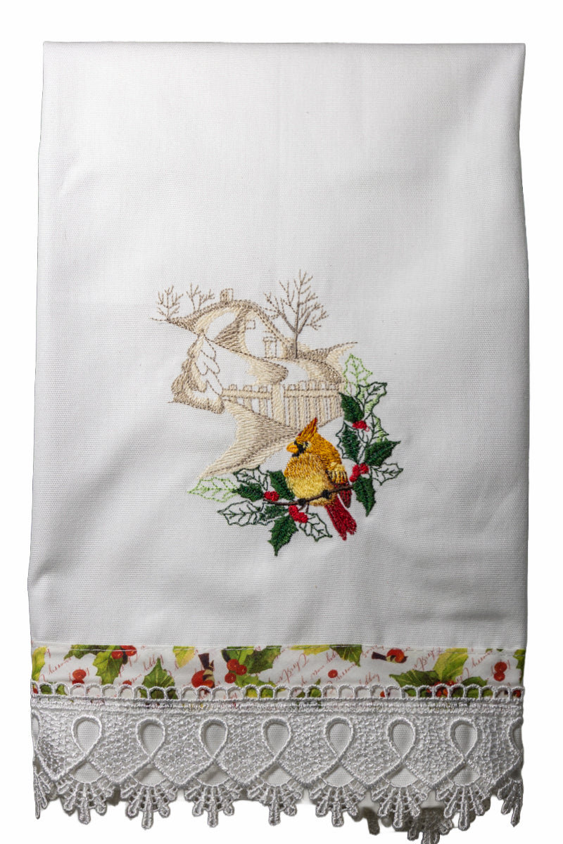 Asciugamano in cotone bianco con ricamo cardinale femmina tra agrifogli e casetta innevata, bordo stampato con bacche rosse e pizzo lavorato.