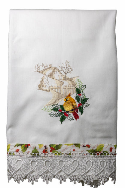 Asciugamano in cotone bianco con ricamo cardinale femmina tra agrifogli e casetta innevata, bordo stampato con bacche rosse e pizzo lavorato.
