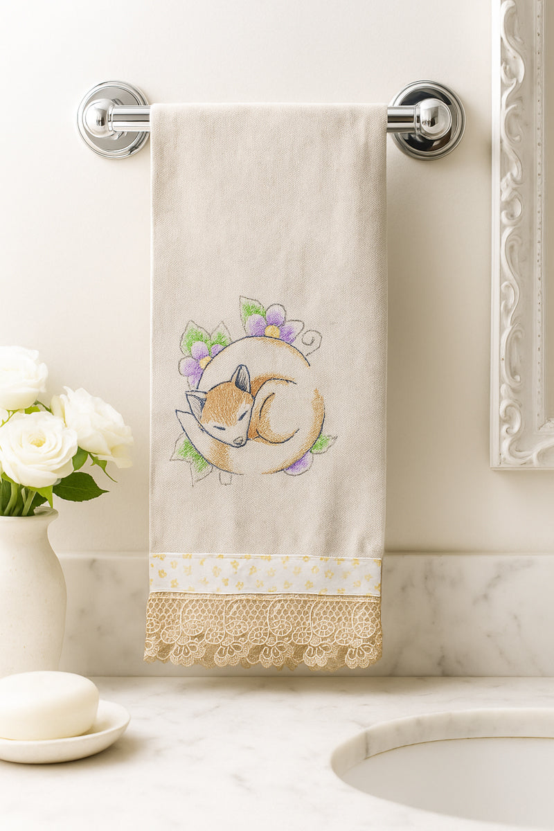 Asciugamano in cotone con ricamo volpe addormentata tra fiori viola e verdi, fotografato appeso in un bagno elegante.