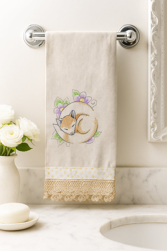 Asciugamano in cotone con ricamo volpe addormentata tra fiori viola e verdi, fotografato appeso in un bagno elegante.