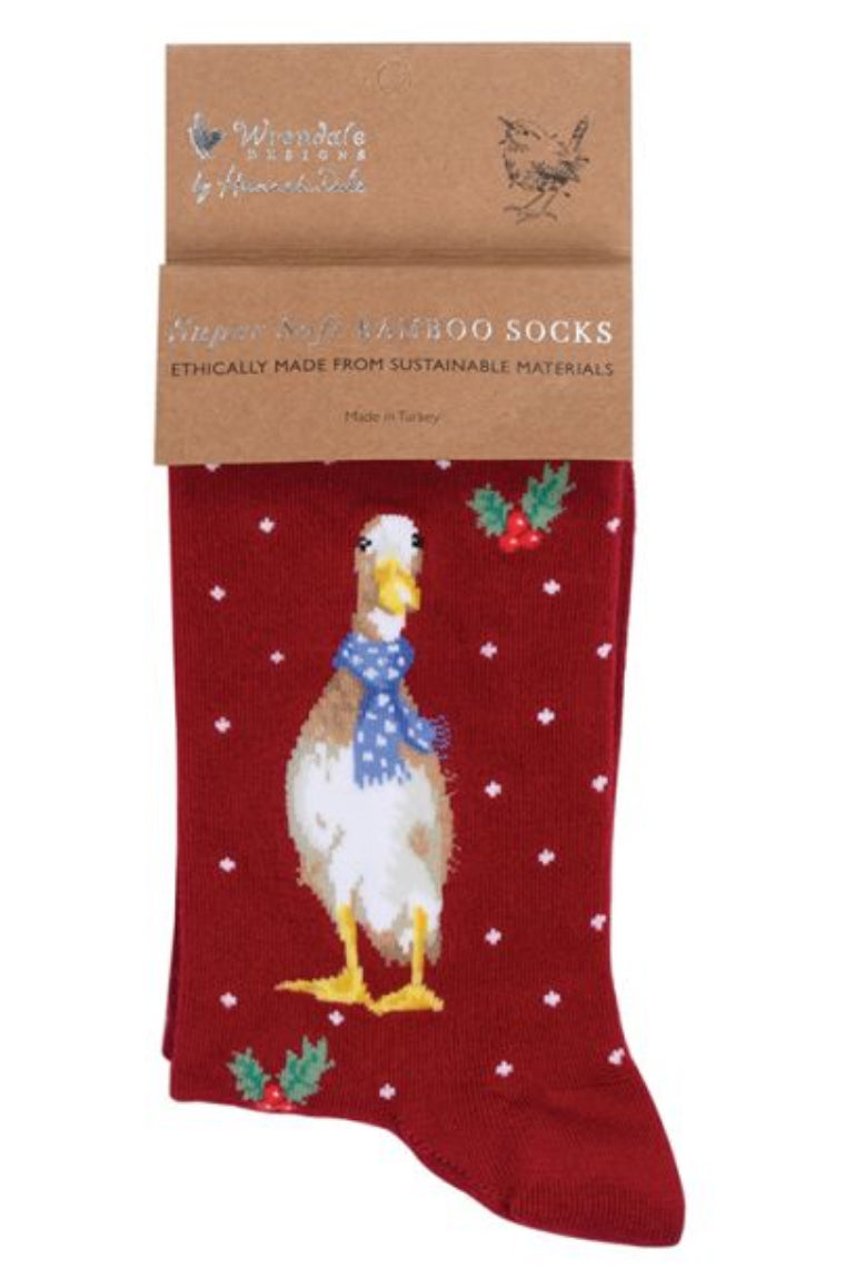 Calza da donna Wrendale Designs in bambù rosso con ricamo di un'anatra natalizia con sciarpa blu a pois, presentata con cartoncino kraft del brand su sfondo neutro.