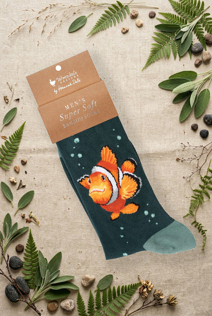 Calza da uomo Wrendale Designs in bambù verde petrolio scuro con pesce pagliaccio arancione ricamato, fotografata su sfondo naturale primaverile.