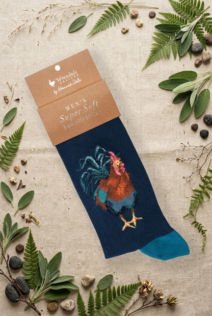 Calza da uomo Wrendale Designs in bambù blu scuro con ricamo di gallo multicolore, fotografata su sfondo naturale primaverile.