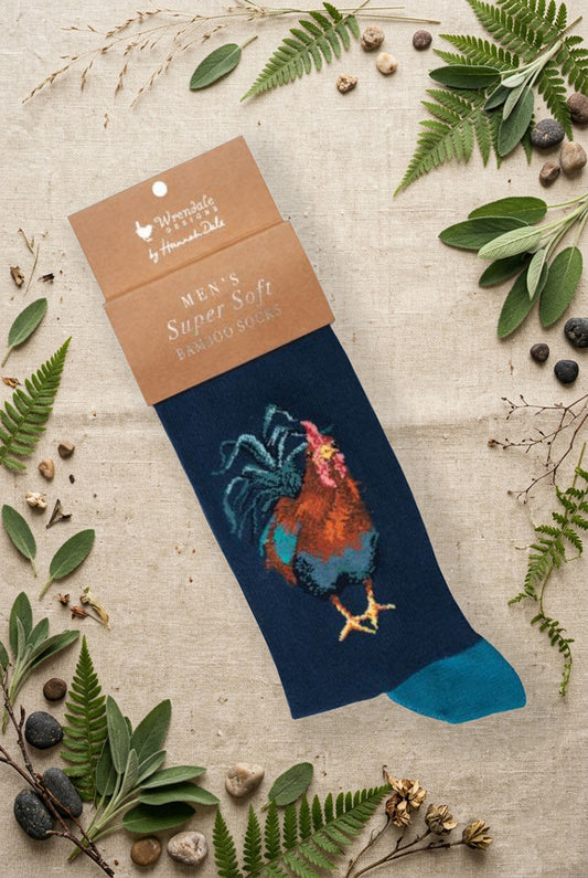 Calza da uomo Wrendale Designs in bambù blu scuro con ricamo di gallo multicolore, fotografata su sfondo naturale primaverile.