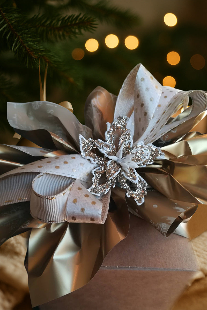 Confezione regalo in cartone kraft con ricca decorazione per palline di Natale in vetro personalizzate, fotografata su fondo festivo con luci soffuse.