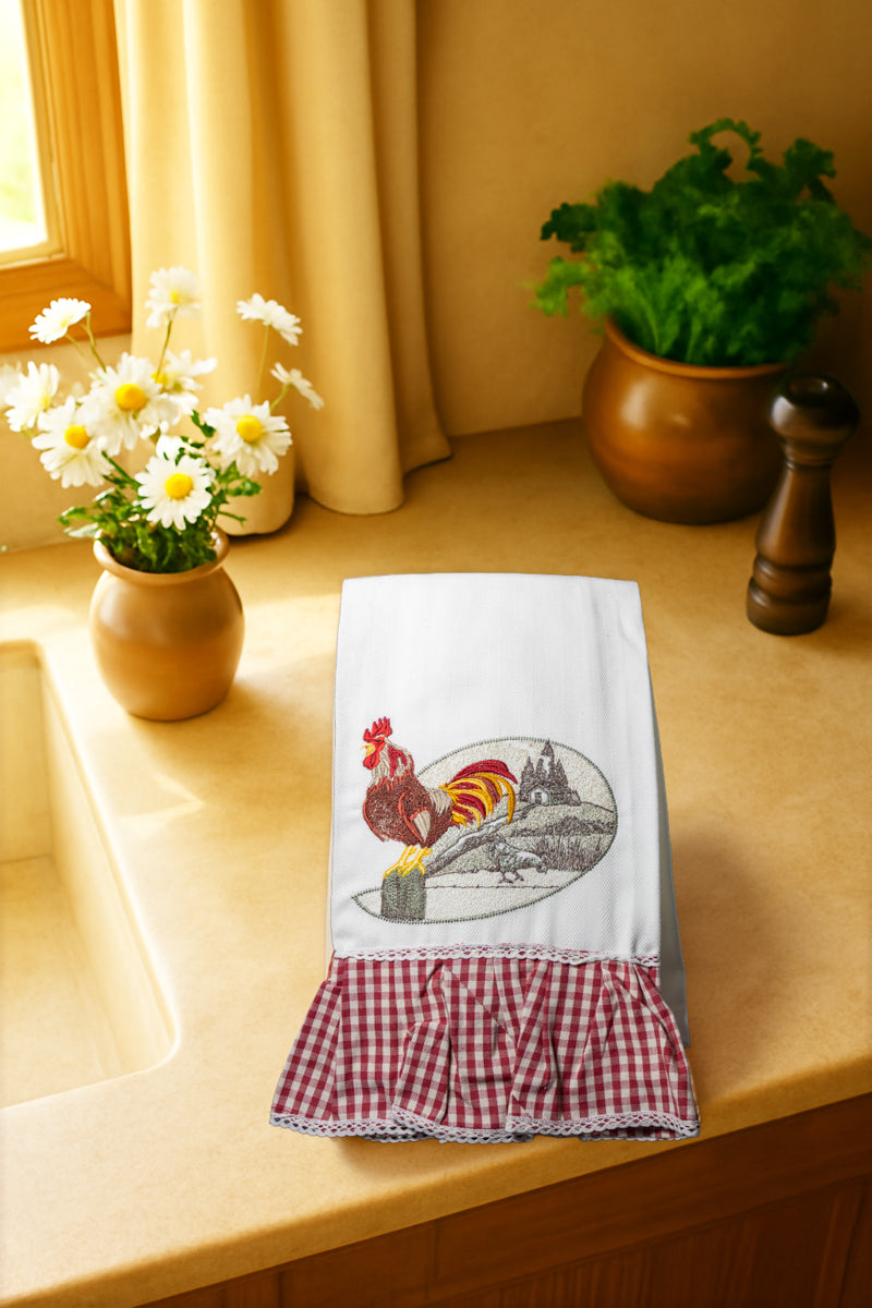 Asciugapiatto Mattine di Campagna Il Casale al Mattino con ricamo gallo davanti a casale rustico immerso nella luce del primo mattino, fotografato dall’alto su piano cucina in legno.
