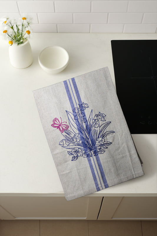 Asciugapiatti ricamato con mughetti e farfalla della collezione Vintage Stripes Fleurs Colorées, fotografato dall'alto in cucina moderna.