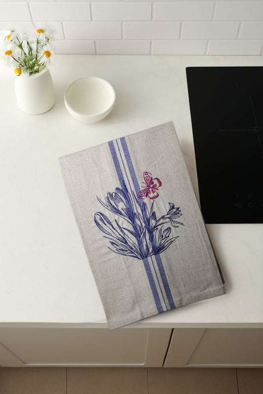 Asciugapiatti ricamato con crocus e farfalla della collezione Vintage Stripes Fleurs Colorées, fotografato dall'alto in cucina moderna.