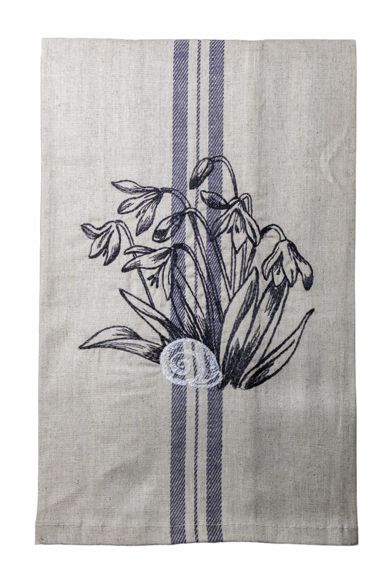 Dettaglio del ricamo Asciugapiatti ricamato con bucaneve e chiocciola della collezione Vintage Stripes Noir Botanique su fondo neutro.