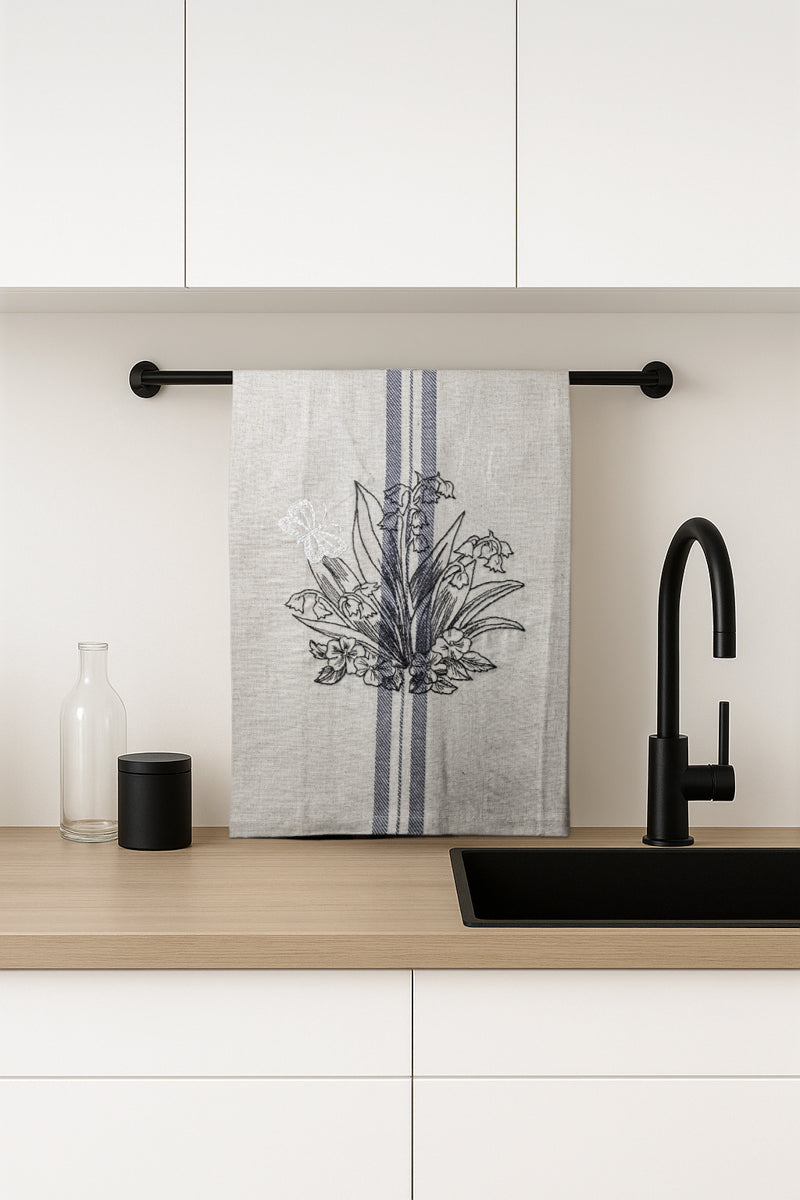 Asciugapiatti ricamato con mughetti e farfalla della collezione Vintage Stripes Noir Botanique, fotografato in cucina moderna.