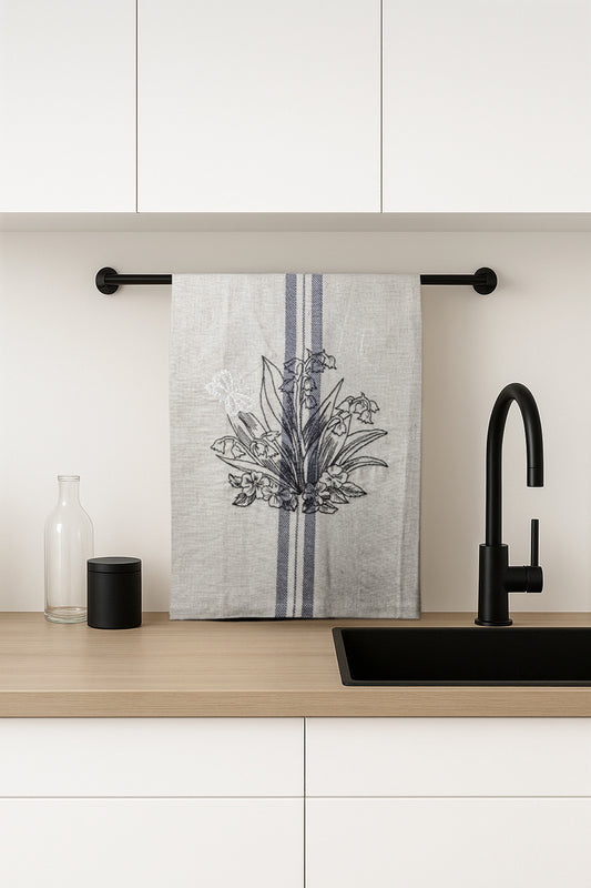 Asciugapiatti ricamato con mughetti e farfalla della collezione Vintage Stripes Noir Botanique, fotografato in cucina moderna.