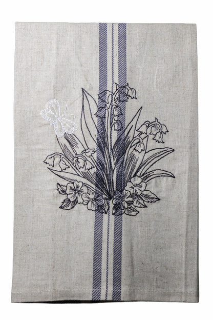 Dettaglio del ricamo Asciugapiatti con mughetti e farfalla della collezione Vintage Stripes Noir Botanique su fondo neutro.