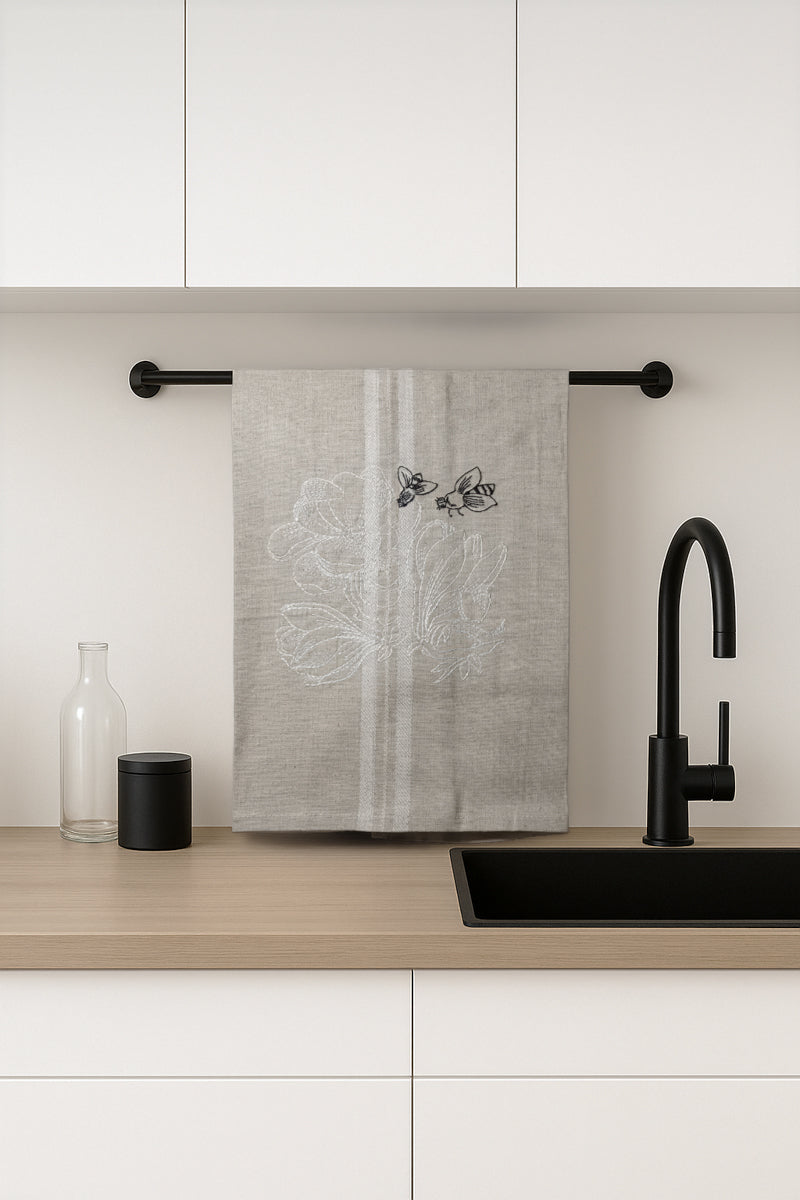 Asciugapiatti ricamato con ranuncoli e api della collezione Vintage Stripes Noir Botanique, fotografato in cucina moderna.