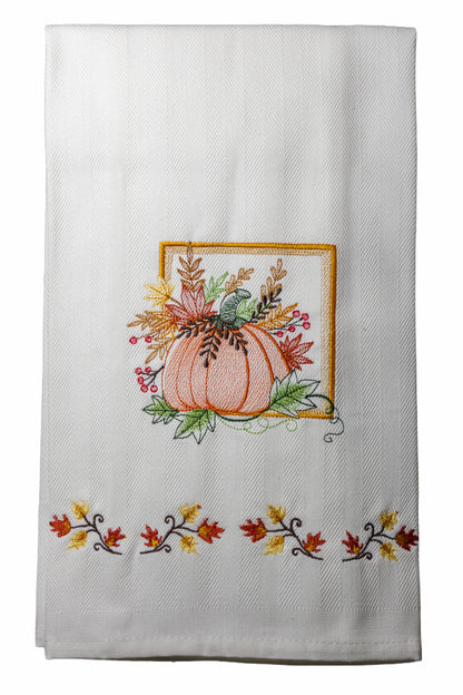 Ricamo zucca autunnale con foglie e bacche su asciugapiatto in cotone bianco, fotografato su sfondo neutro.