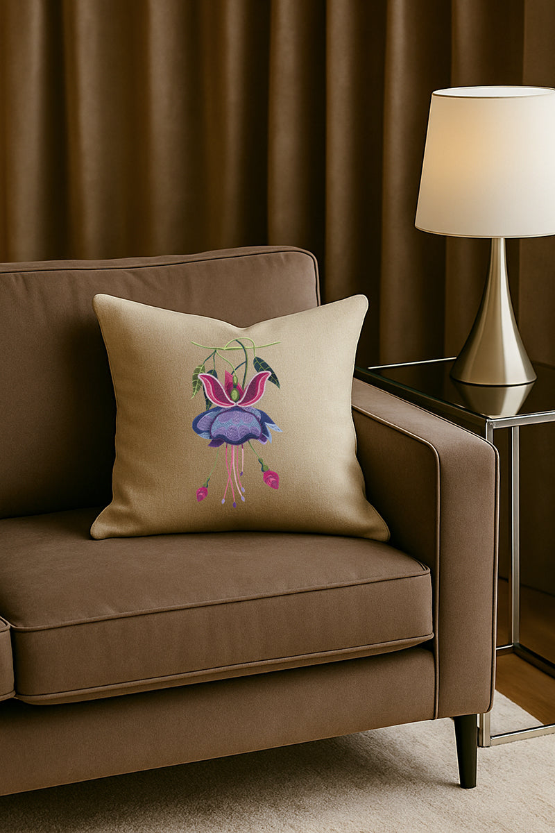 Cuscino in misto lino beige con ricamo 3D di fucsia viola, posato su un divano marrone in un soggiorno elegante con lampada dorata e tende scure.