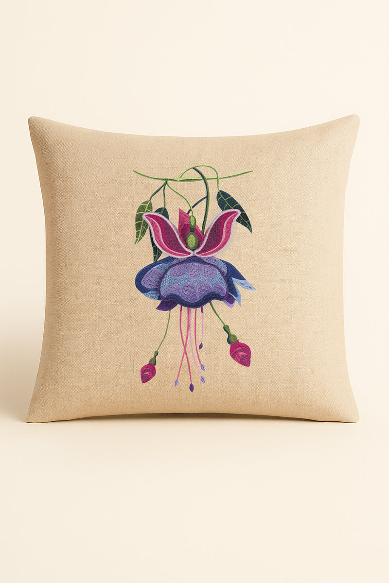 Cuscino quadrato in misto lino beige fotografato su sfondo neutro, con ricamo a rilievo di fucsia viola e foglie verdi, in stile artigianale.