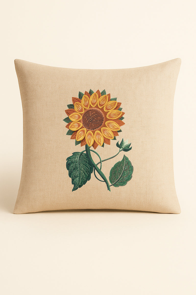Cuscino quadrato in misto lino beige fotografato su sfondo neutro, con ricamo tridimensionale di girasole giallo e foglie verdi, in stile artigianale.