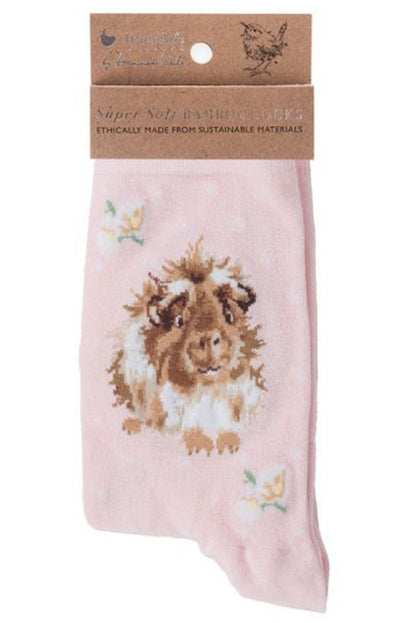 Calza da donna Wrendale Designs in bambù rosa cipria con ricamo di porcellino d'India e piccoli fiori, presentata con cartoncino kraft del brand su sfondo neutro.