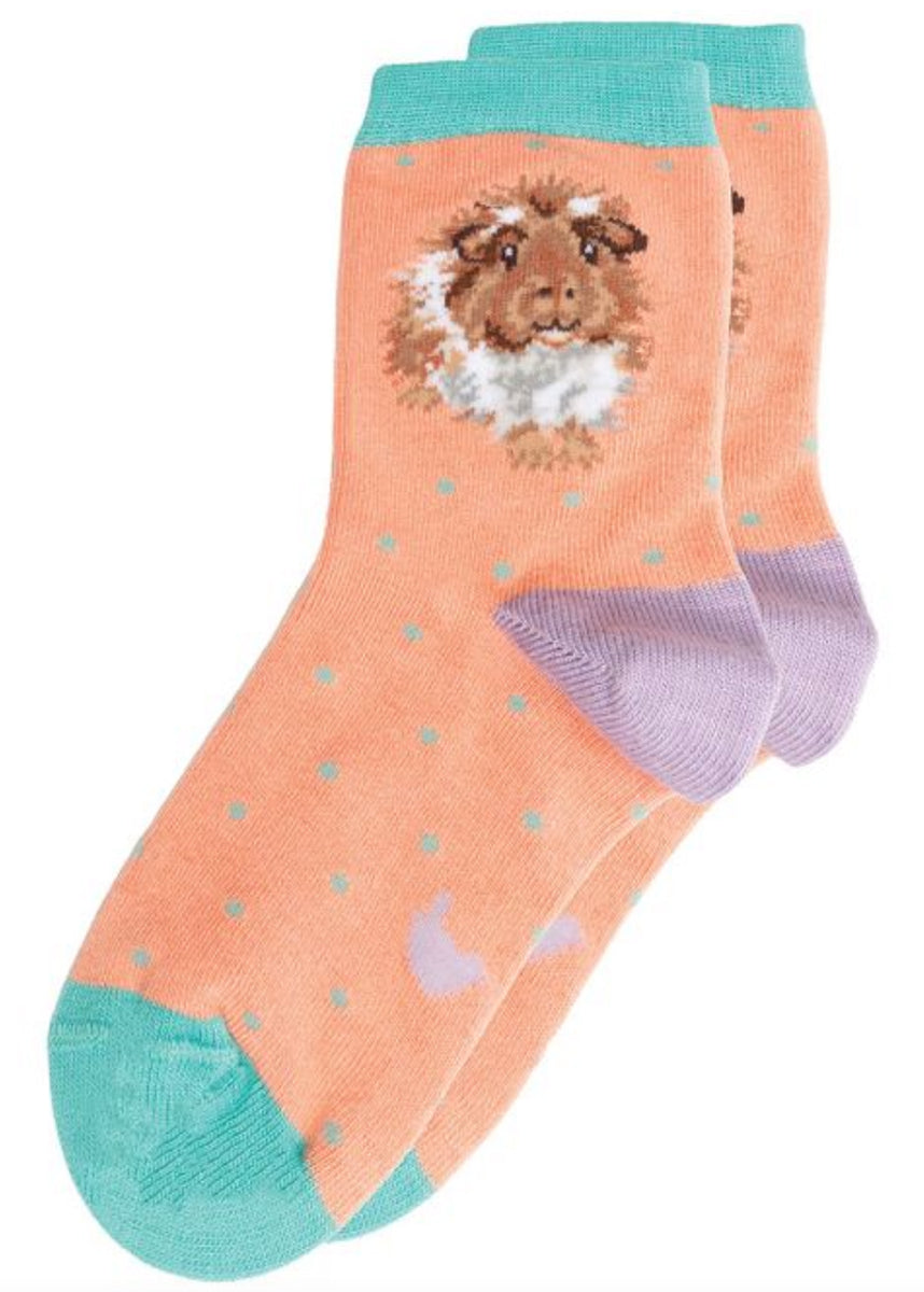 Coppia di calze Wrendale Designs da bambini color pesca con polsino verde acqua e tallone lilla, decorate con porcellino d’India e piccoli pois, su sfondo bianco.