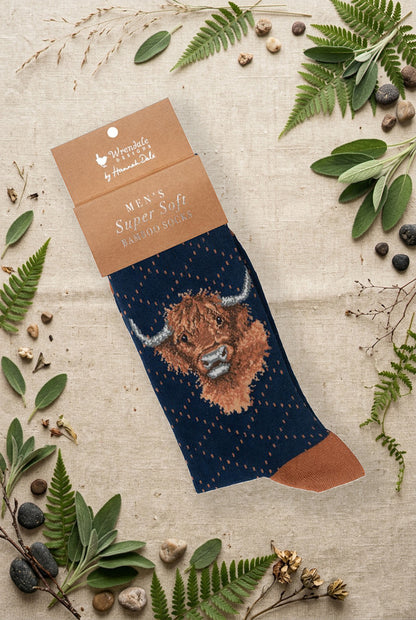 Calza da uomo Wrendale Designs in bambù blu notte profondo con mucca delle Highlands ricamata, fotografata su sfondo naturale primaverile.