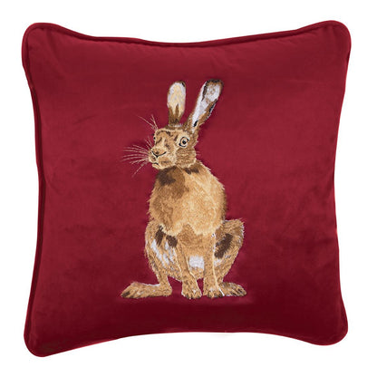 Cuscino in velluto rosso Wrendale Designs con ricamo di una lepre seduta, fotografato su sfondo bianco.