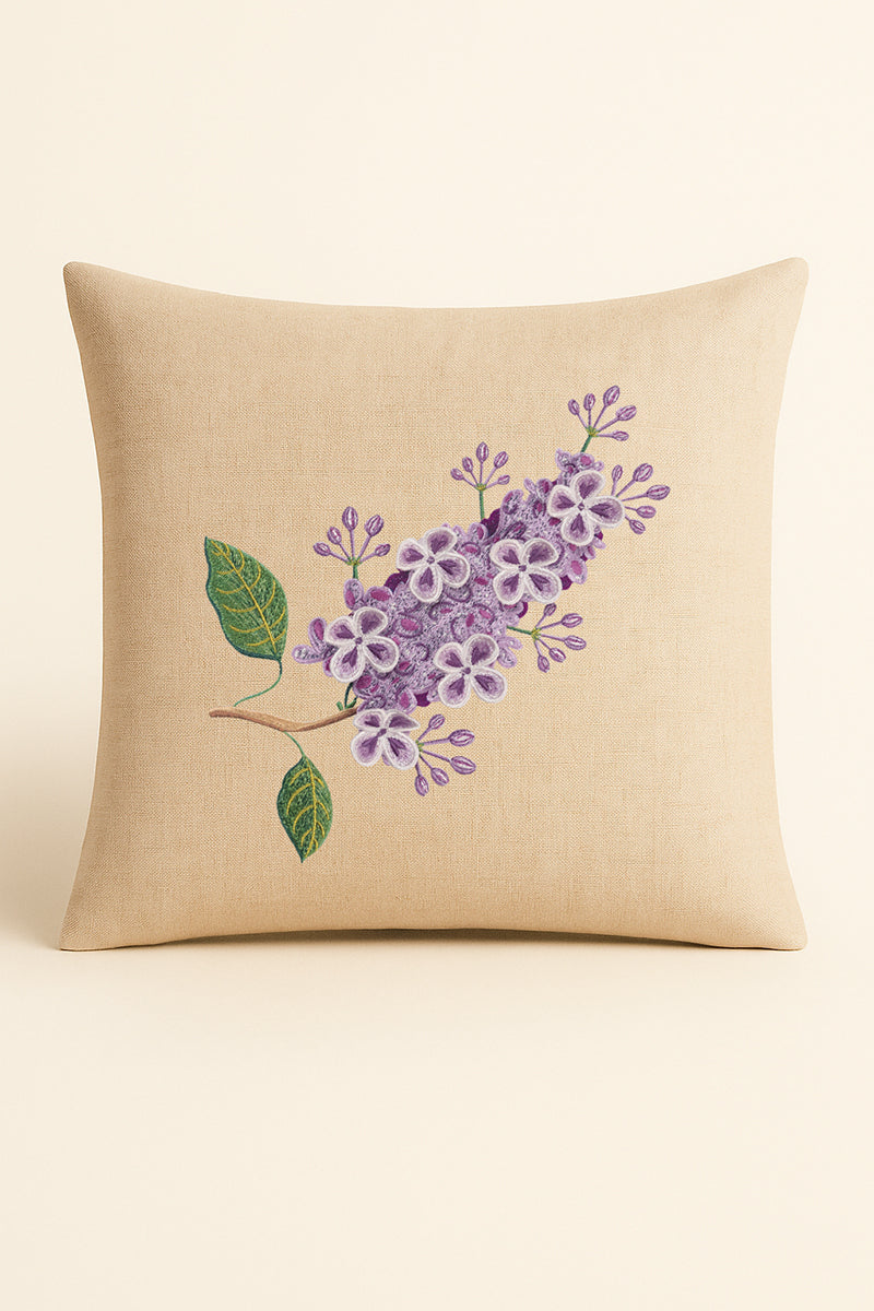 Cuscino quadrato in misto lino beige, fotografato su sfondo chiaro, con ricamo 3D di lillà lilla e foglie verdi realizzato con tecnica artigianale.