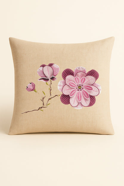 Cuscino quadrato in misto lino beige fotografato su sfondo neutro, con ricamo a rilievo di magnolia rosa, boccioli e foglie verdi in stile artigianale.