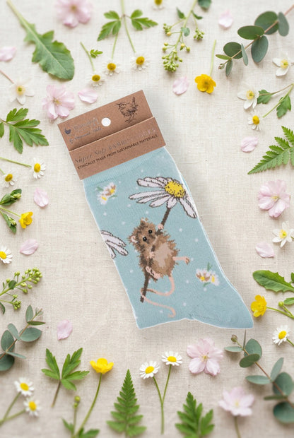 Calza da donna Wrendale Designs in bambù verde acqua con topolino su margherita ricamato e pois bianchi, fotografata su sfondo primaverile con fiori e foglie.