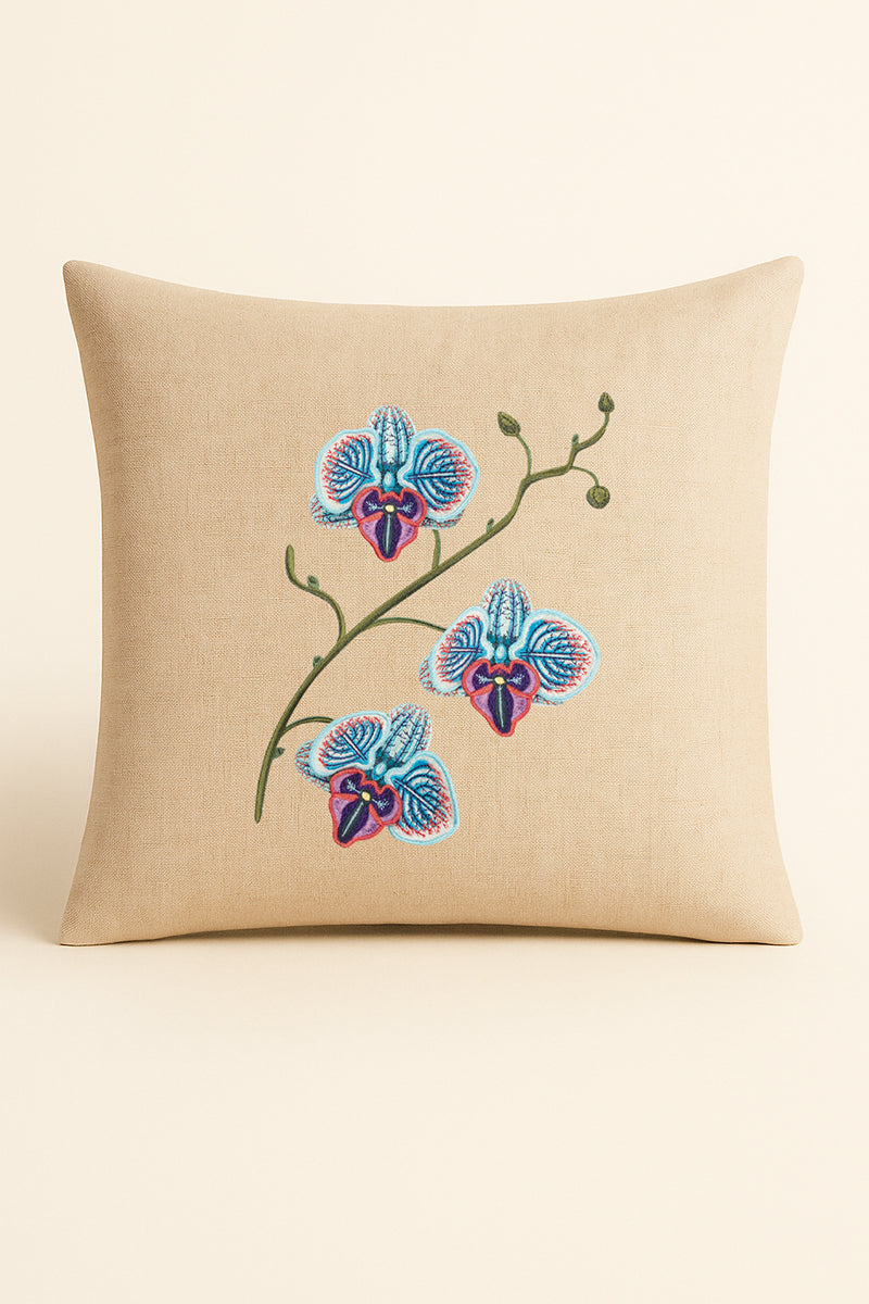 Cuscino quadrato in misto lino beige fotografato su sfondo neutro, con ricamo dettagliato di orchidea blu, turchese e porpora realizzato con tecnica artigianale.