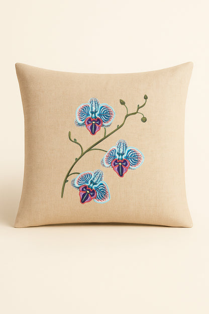 Cuscino quadrato in misto lino beige fotografato su sfondo neutro, con ricamo dettagliato di orchidea blu, turchese e porpora realizzato con tecnica artigianale.