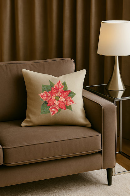 Cuscino in misto lino beige con ricamo tridimensionale di stella di Natale rossa, posato su un divano marrone in un soggiorno elegante con lampada dorata e tende scure.
