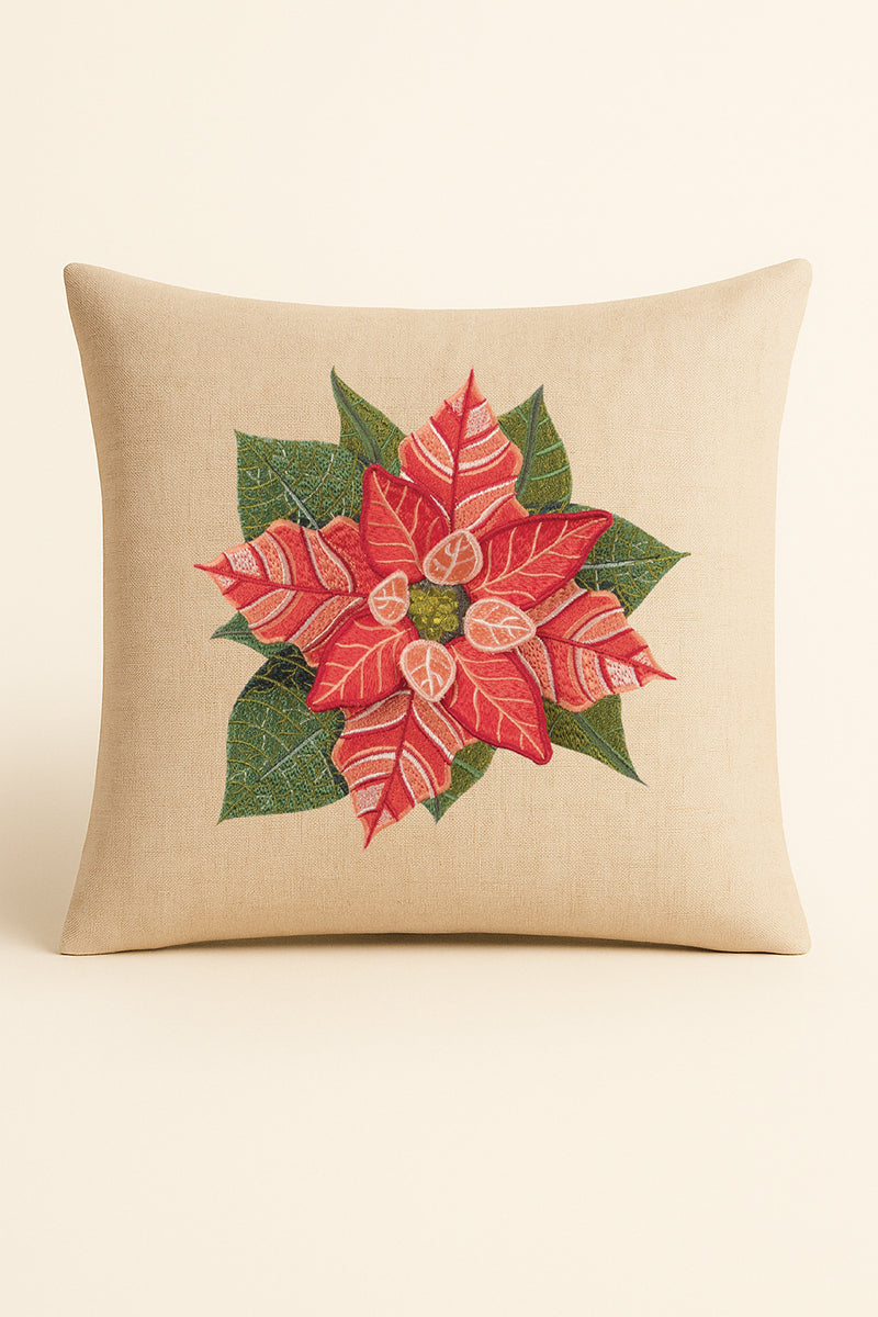 Cuscino quadrato in misto lino beige fotografato su sfondo neutro, con ricamo dettagliato e tridimensionale di stella di Natale rossa e foglie verdi.
