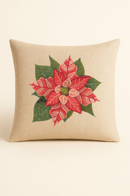 Cuscino quadrato in misto lino beige fotografato su sfondo neutro, con ricamo dettagliato e tridimensionale di stella di Natale rossa e foglie verdi.