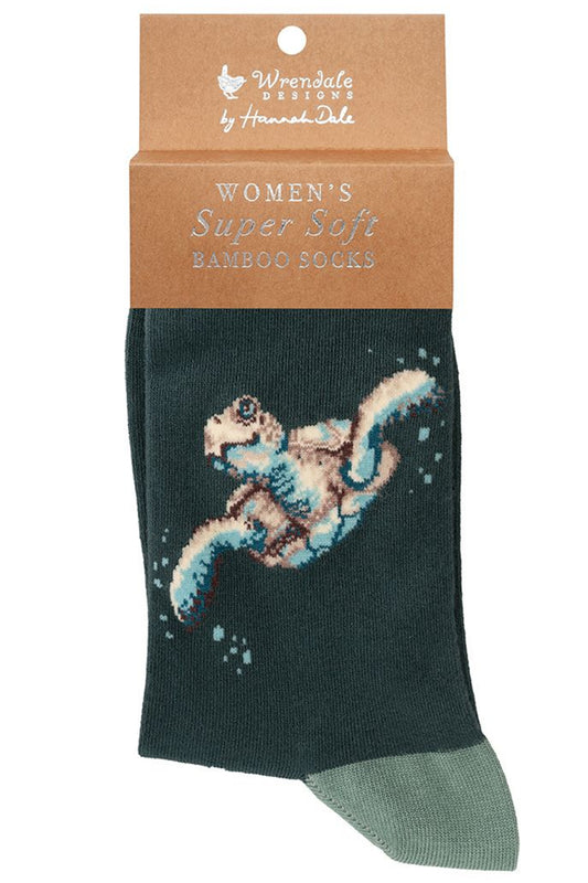 Calza da donna Wrendale Designs in bambù blu petrolio con tartaruga marina ricamata, presentata con cartoncino kraft del brand su sfondo neutro.