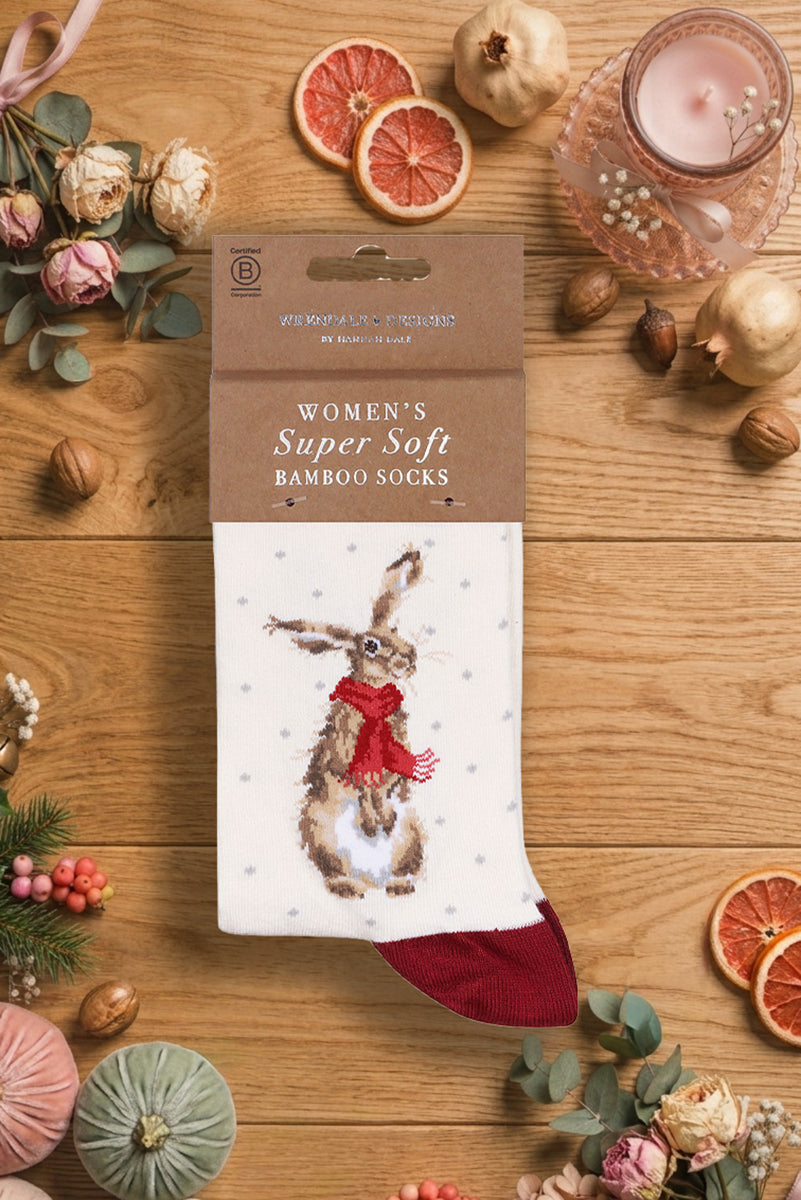 Calza da donna Wrendale Designs in bamboo panna con lepre ricamata con una sciarpa rossa, fotografata su sfondo festivo