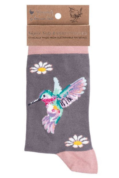 Calza da donna Wrendale Designs in bambù grigio con ricamo di colibrì colorato e margherite bianche, presentata con cartoncino kraft del brand su sfondo neutro.